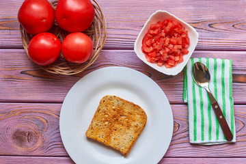 Toasted toasts and chopped tomatoes. Vegetarian bruschetta cooking with fresh tomatoes and pepper...