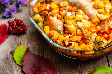 Autumn foodie, roasted chicken with pumpkin, carrots, potatoes and spices in glass pan. Selective focus. Shallow depth of fied.