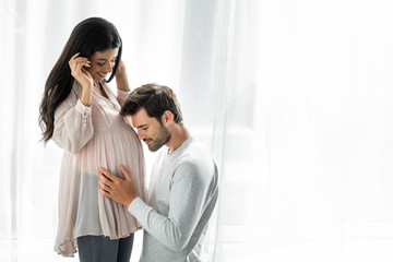 handsome man hugging belly of his pregnant african american woman