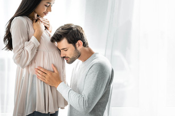 handsome man hugging belly of his pregnant african american woman