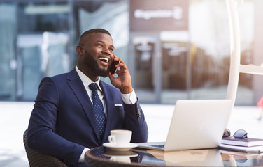 Happy Entrepreneur Speaking On Phone Working In Outdoor Cafe