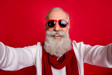 Excited aged santa man making self photos wear sun specs knitted jumper isolated red background