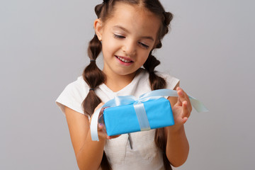 Nice little girl holding a blue gift box in her hands.