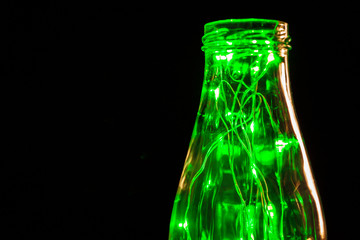 Green garland with light bulbs put in glass storage jar