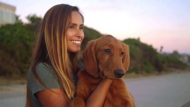 Young cute girl smiling watching sunset with golden retriever puppy