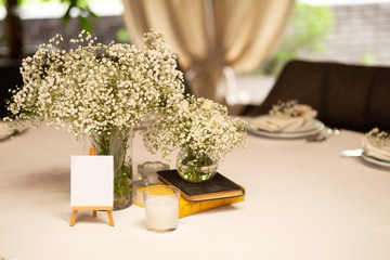 Table setting for  banquet in restauran with white flowers. A beautiful table for any occasion, holiday, wedding or party. Empty  card for  guest names.