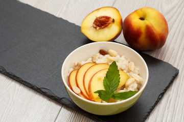 Sorghum salad with nuts and fresh peach on stone board.
