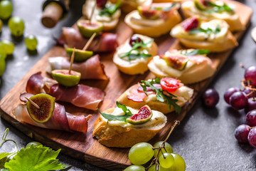 Assorted brushetta - italian apetizer or traditional spanish tapas for sharing. Party food on catering platter. Antipasti with meat, cheese and fruits.