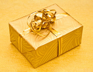 Golden gift on gold surface, high angle view