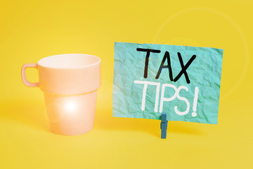 Handwriting text Tax Tips. Conceptual photo compulsory contribution to state revenue levied by government Cup empty paper blue clothespin rectangle shaped reminder yellow office