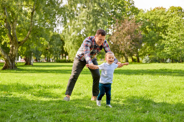 Obraz premium family, fatherhood and people concept - happy father with little son playing in summer park