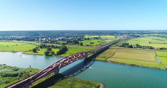 A Yellow Blue Intercity Train Crossing the Hanzeboog Bridge Over the Dutch IJssel River, The Netherlands, 4K Drone Footage