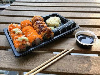 Sushi Set in Plastic Container Box / Package. California Roll, New York Roll, Boom Roll, Ginger, Wasabi and Soy Sauce.