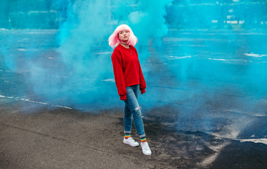 Ethnic teenager walking against blue smoke