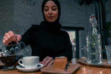 Muslim woman in cozy cafe enjouing her weekend. Concept of living full life with contemporary modern attitude from tolerable society. Active lifestyle of muslim woman.