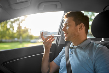 transport, technology and communication concept - male passenger using voice command recorder on...