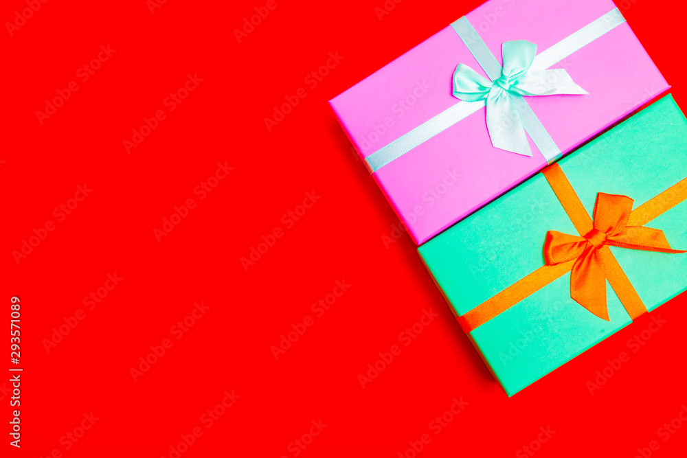 Poster colored boxes with ribbons on a red background. view from above.