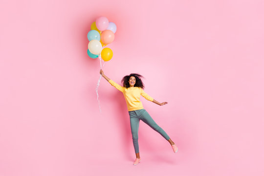 Full length photo of funky childish dreamy african girl hold many balons try fly in air enjoy holidays anniversary wear good look outfit sneakers isolated over pink color background