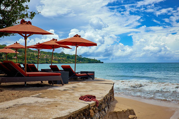 Tropical beach panorama with deckchairs, umbrellas, boats and palm tree