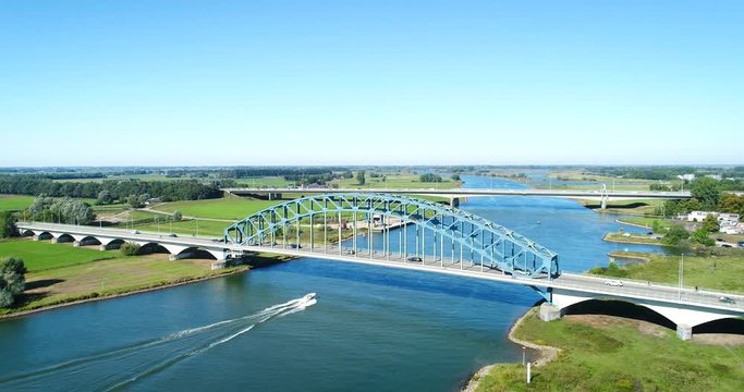 The Dutch IJssel River Near Zwolle With Two Bridges, A Fast Little Boat Going Underneath It, The Netherlands, 4K Drone Footage
