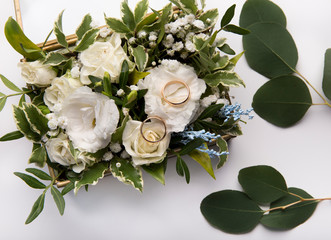 Obraz na płótnie Canvas Wedding rings with bridal bouquet on white background
