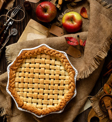 overhead shot of homemade thanksgiving warm baked apple lattice pie crust on sackcloth on rustic...