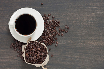 Black coffee in a cup of coffee and coffee beans placed on the old table Top view with empty space for your message