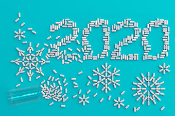 A lot of pills scattered on a blue background in the form of snowflakes and numbers 2020. 3D illustration