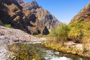 Mountain landscape in Uzbekistan. Stones and river.Autumn in the mountains, yellow trees near the river. Fresh air.