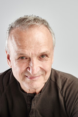 Portrait of a Caucasian elderly man smiling on a white studio background. Handsome gray-haired old pensioner with a friendly kind face