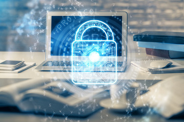 Double exposure of desktop with computer and lock icon hologram. Concept of data safety.