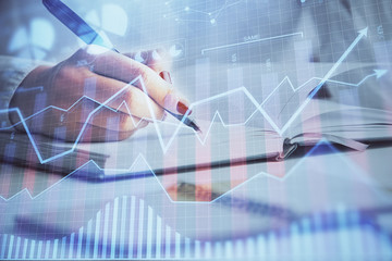 Multi exposure of woman's hands making notes with forex graph hologram. Concept stock market analysis.