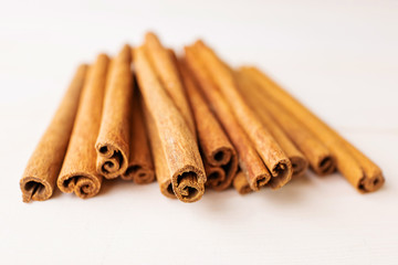 Cinnamon sticks on a white wooden background close-up. The concept of spices for baking, drinks and other dishes. Minimalism, place for text.