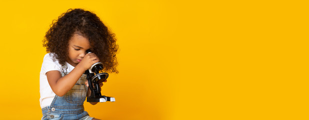 Early education concept. Kid girl looking through microscope