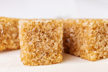 Cane sugar cubes on a white wooden background close-up. Minimalism, place for text. Macro