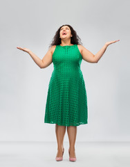 people and emotion concept - happy amazed woman in green dress looking up over grey background