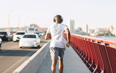 Sporty black guy running along the bridge