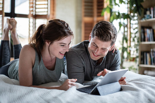 Young adult couple looking at a digital tablet together in bed