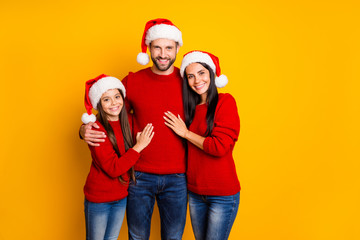 Photo of cute affectionate adorable family smiling toothily hugging each other wearing jeans denim santa cap headwear smiling toothily isolated over vivid color yellow background