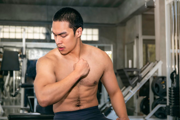 Fototapeta na wymiar Power muscular handsome Asian man strong and healthy smiling in gym after workout.