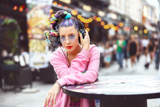 Cool funky young girl listening music on headphones on city streets