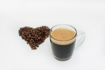 a Cup of fresh coffee and a heart made of coffee beans on a white background