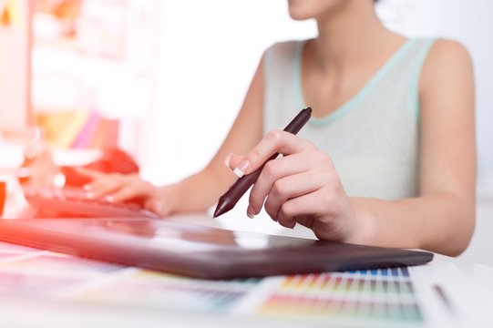 Hand of the designer with a pen on a tablet