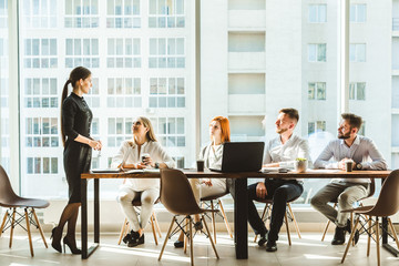 A team of young businessmen working and communicating together in an office. Corporate businessteam and manager in a meeting. desktop against the background of the pan window, free space for text