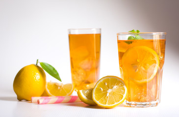 Glasses of ice tea with lemon slices and mint on white background