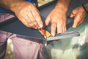 Tinsmith marking the cutting angles with measuring tape