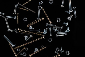 top view of scattered nuts, bolts and studs isolated on black