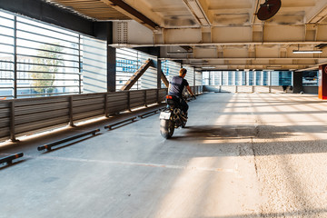 Distant plan of biker riding motorcycle at parking. Urban background.