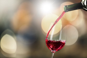 Red wine pouring in glass on background, close-up view