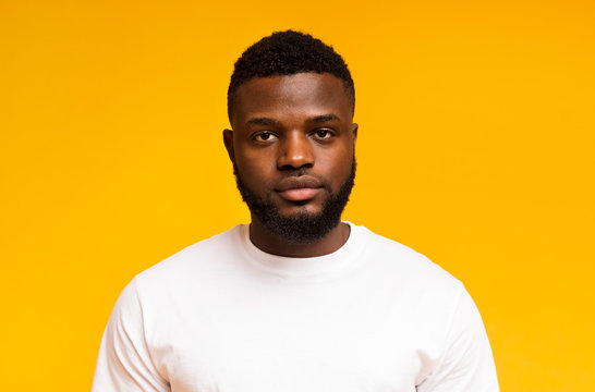 Serious young african american man portrait on yellow background